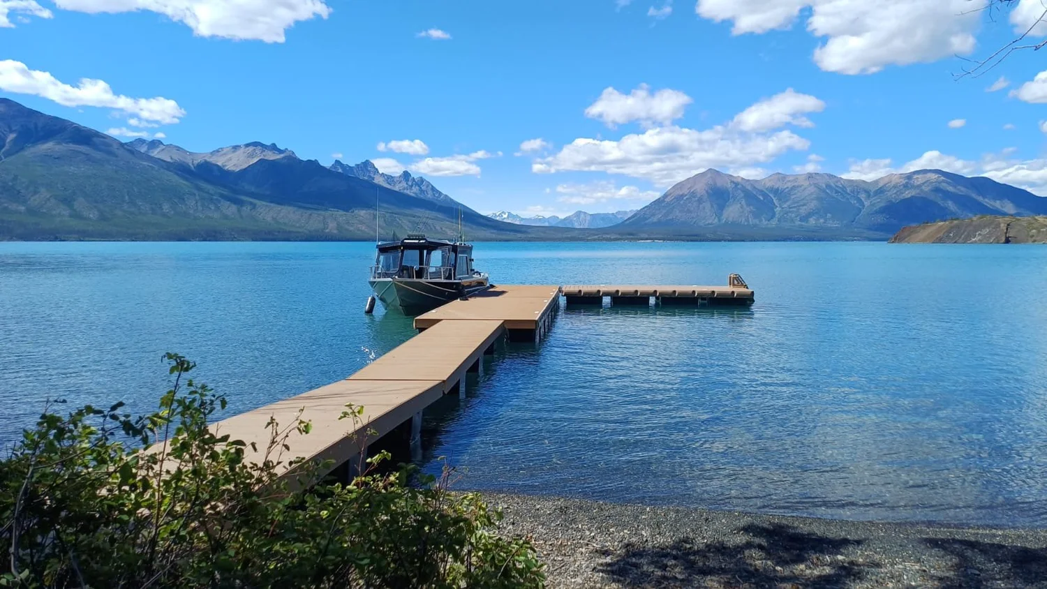 Boat moored at the lodge dock on turquoise Chilko Lake beneath mountains