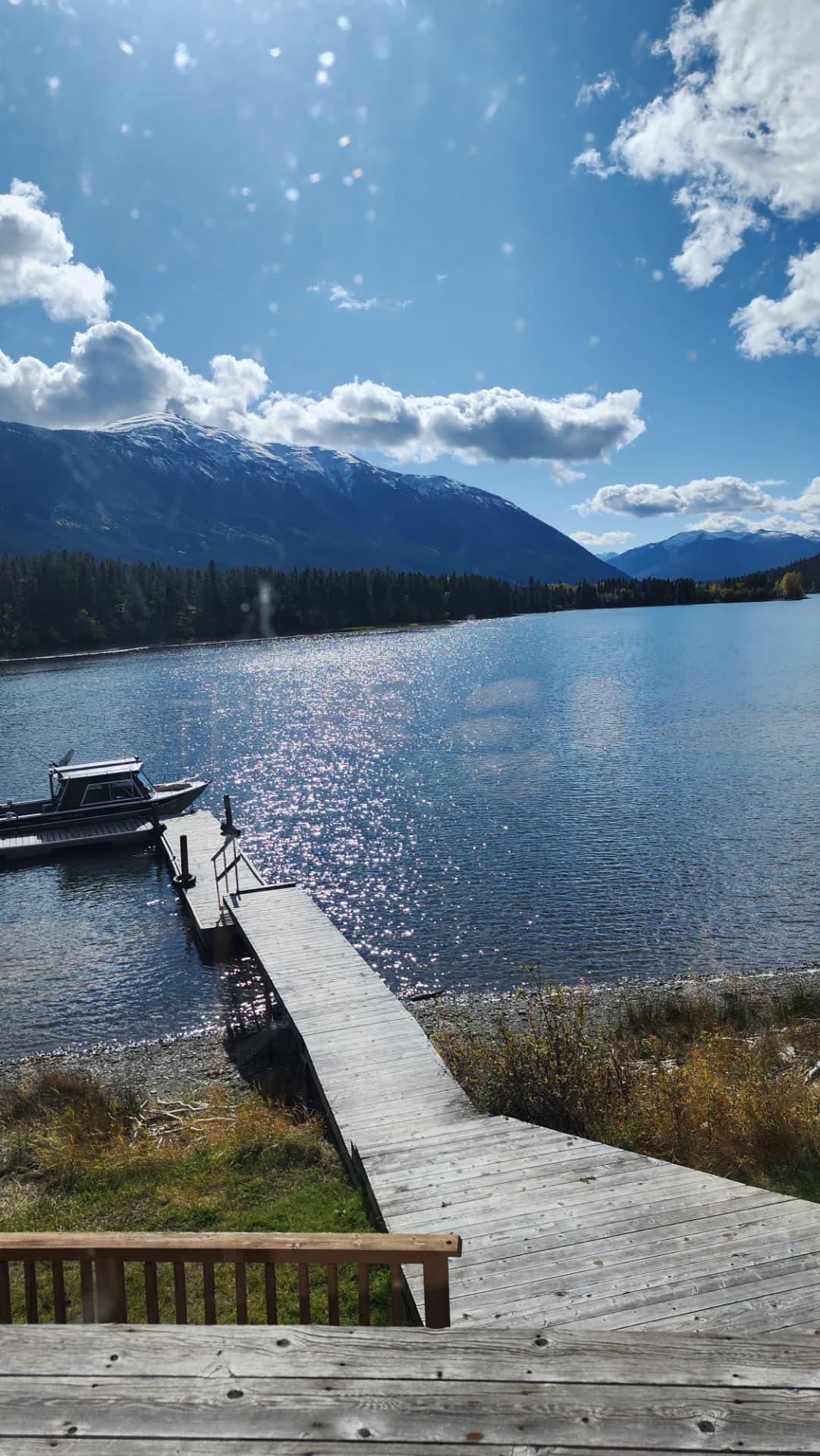 Dock and boat on Chilko Lake beneath snow-capped peaks