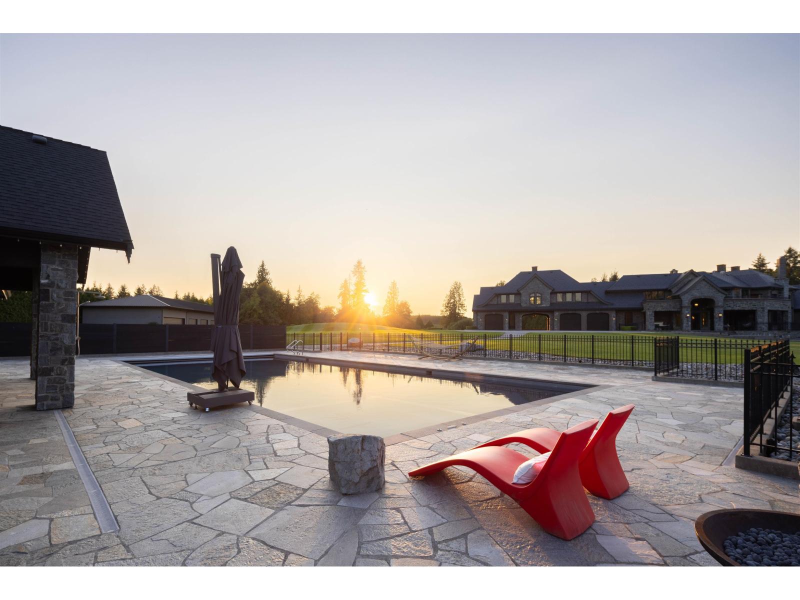 Outdoor pool and stone terrace at sunset, with the estate beyond