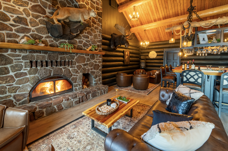 Great room with stone fireplace, log walls and leather seating inside the lodge