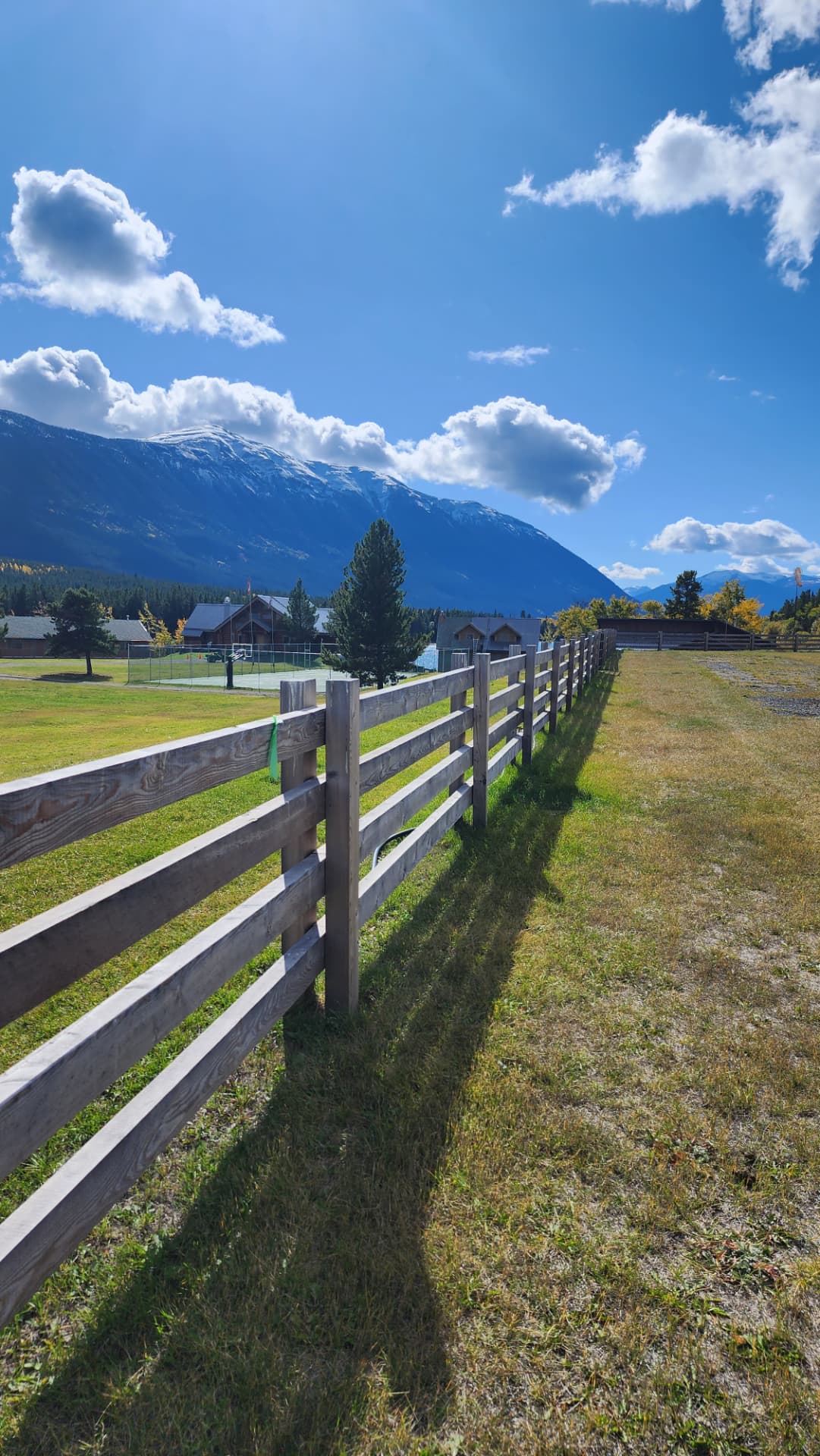 Split-rail fence crossing the lodge meadow toward the mountains